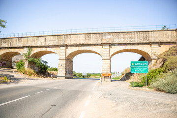 Canal de Aragón y Cataluña - Canal of Aragon and Catalonia aqueduct over the A-140 paved road at the border between Catalonia and Aragon, Spain - obrazy, fototapety, plakaty