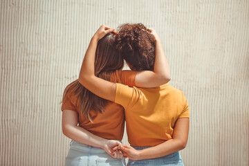 Strong female friendship. Rear view two girls best friends holding hands behind back and hugging