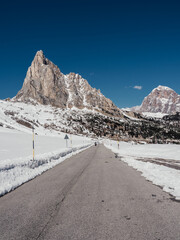 a mountain road in the middle of the snow with a blue sky above it