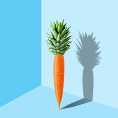 Carrot with pineapple leaves on pastel blue background. Easter m