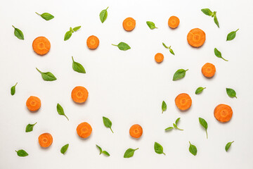 Colorful pattern made of sliced carrots and basil green leaves. Minimal food concept.