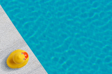 Yellow rubber duck near to the pool. Summer minimal concept.