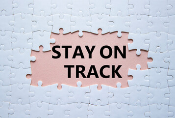 Stay on track symbol. Concept words Stay on track on white puzzle. Beautiful pink background. Business and Stay on track concept. Copy space.