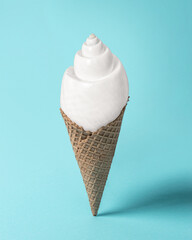 Creative composition with seashell and ice cream cone on pastel blue background. Summer minimal concept.