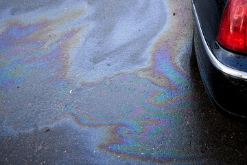 Obraz premium Leakage of oil or gasoline from the car on the asphalt in the parking lot.