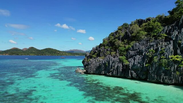 Aerial view of tropical Philippines island. White sand beach, rocks cliffs mountains with blue bay and coral reef, 4k