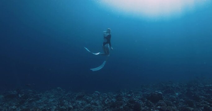 Woman freediver glides on deep ocean. Freediving in blue ocean