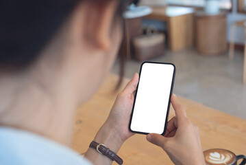 Mockup, woman's hands holding mobile phone with blank screen in coffee shop, over shoulder view