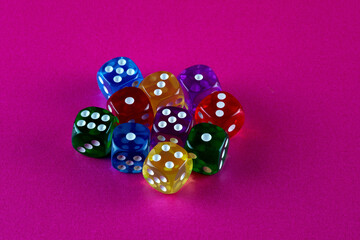 Colourful Plastic Dice Cubes on a Pink Table Surface - 703979851
