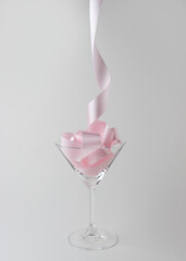 Martini glass with pink party ribbon. Minimal celebration concept.