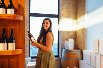 Young charming woman with long beautiful hair smiles and holds a bottle of wine.