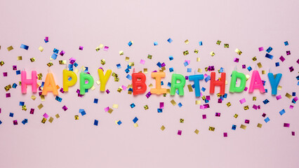 Colorful celebration background with various party confetti and candle decoration. Minimal birthday concept. Flat lay.