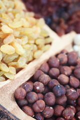 Shelled hazelnuts and raisins on a wooden tray close-up