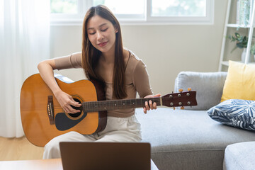 Hobby relaxation concept, happy asian young woman in casual clothes, playing acoustic guitar with...