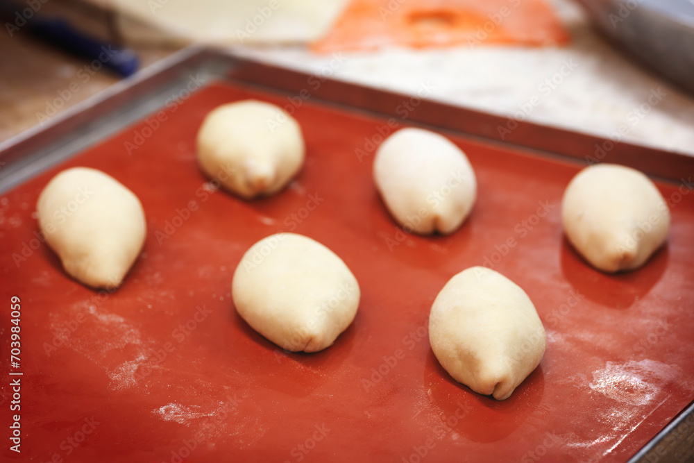 Poster many pastry bun pies lie on a baking sheet before frying in the oven