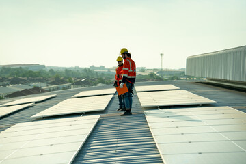 Specialist technician professional engineer checking top view of installing solar roof panel on the factory rooftop under sunlight. Engineers having service job of electrical renewable eco energy - obrazy, fototapety, plakaty