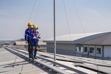 Specialist technician professional engineer checking top view of installing solar roof panel on the factory rooftop under sunlight. Engineers having service job of electrical renewable eco energy