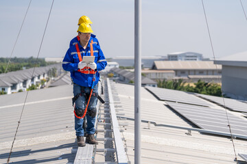 Specialist technician professional engineer checking top view of installing solar roof panel on the factory rooftop under sunlight. Engineers having service job of electrical renewable eco energy