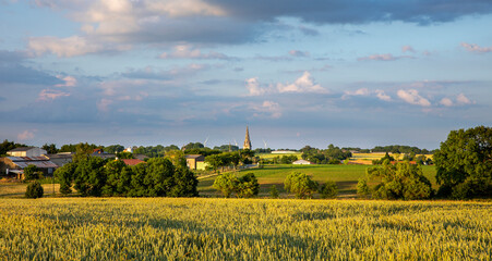 Campagne et village avec son clocher au milieu des champs en France.