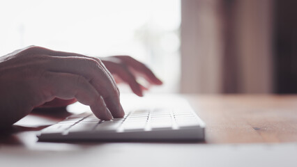 Sideview of a man's hand typing on a computer keyboard, busy with Internet browsing and email....