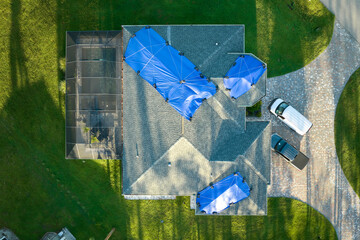 Hurricane Ian damaged house rooftop covered with protective plastic tarp against rain water leaking...