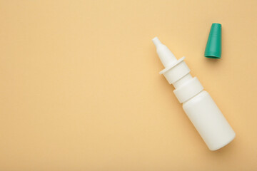 Bottle of nasal drops on beige background. Space for text