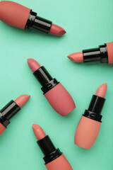 Obraz premium Different pastel lipsticks on mint background. Vertical photo