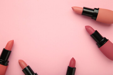 Different pastel lipsticks on pink background. Space for text