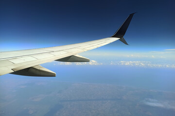 View through airplane window of commercial jet plane wing flying high in the sky. Air travelling concept