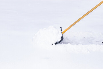an unrecognizable man cleans snow with a shovel in a snowfall