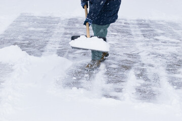 an unrecognizable man cleans snow with a shovel in a snowfall