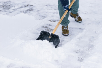 an unrecognizable man cleans snow with a shovel in a snowfall. close-up © Anton Vakhrushev