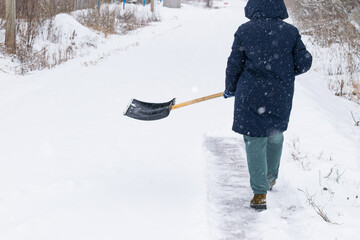 an unrecognizable man cleans snow with a shovel in a snowfall