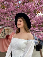 portrait of a woman in a hat next to cherry blossom