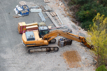Excavator machine stopped at construction site with construction equipment and material