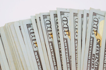 Close up of American hundred dollars bills, vertically fanned out on a white background.