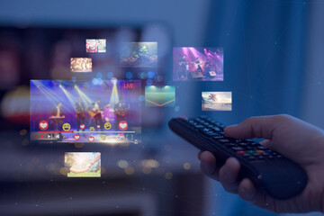 Close-up of hands using remote smart tv on blurred smart tv with video on demand as background