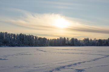 Very cold  January winter day scenery (-21ºC). Sun is shining just above horizon behind the clouds.   