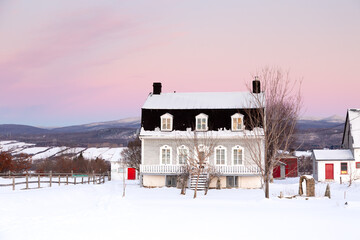 Sunrise winter view of beautiful patrimonial brick country house with metal Mansard roof and dormer...