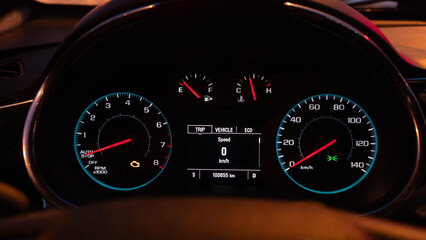 A speedometer and engine error indicator on the dashboard of the car in the evening