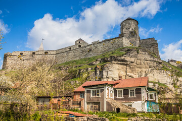 Old Kamianets-Podilskyi Castle under the blue sky. Part of the powerful bastions of the castle. The fortress located among the picturesque nature in the historic city of Kamianets-Podilskyi, Ukraine - obrazy, fototapety, plakaty