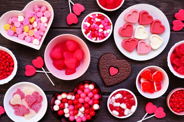 Valentines Day candy table scene with a variety of sweets. Above view on a dark wood background.