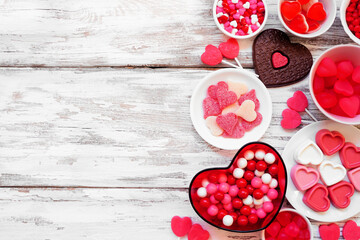 Valentines Day candy side border with a collection of sweets. Above view on a white wood background...