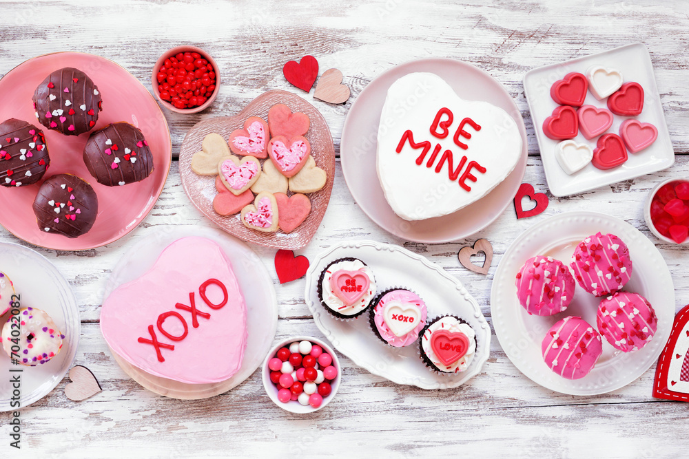 Poster valentines day table scene with a selection of fun desserts and sweets. above view on a white wood b