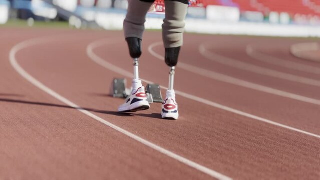 Asian para-athlete with prosthetic blades leg in stadium practicing workout for Paralympic running competition. Amputee sportsman runner practicing running workout. Disabled athlete man sport concept.
