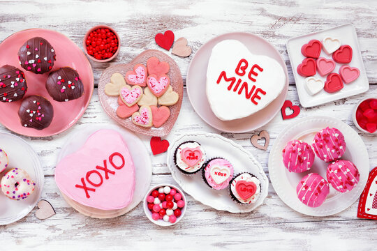Valentines Day table scene with a selection of fun desserts and sweets. Above view on a white wood background. Love and hearts theme. - Powered by Adobe