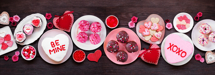 Valentines Day table scene with an assortment of fun desserts and sweets. Overhead view on a dark...