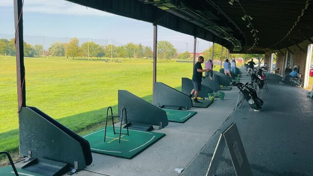 Golfers at the Driving Range, Golfers practicing swings at a driving range on a clear day.