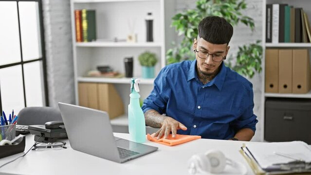 Passionate young latin business worker spructures up his office, serious man cleaning his desk with efficiency