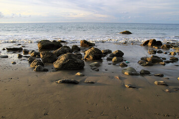 Black rocks on sandy beach